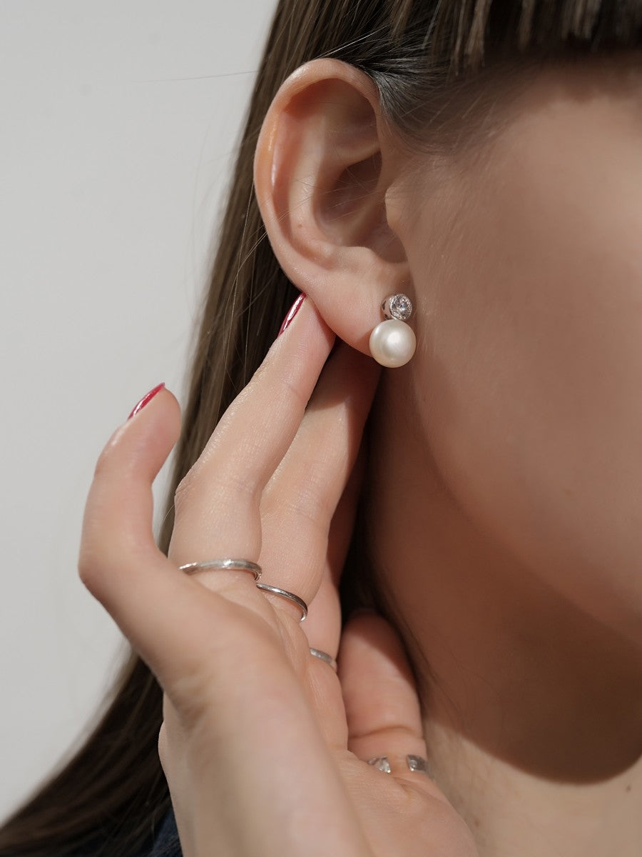 Strieborné náušnice zdobené zirkónom a sladkovodnou perlou detail na uchu